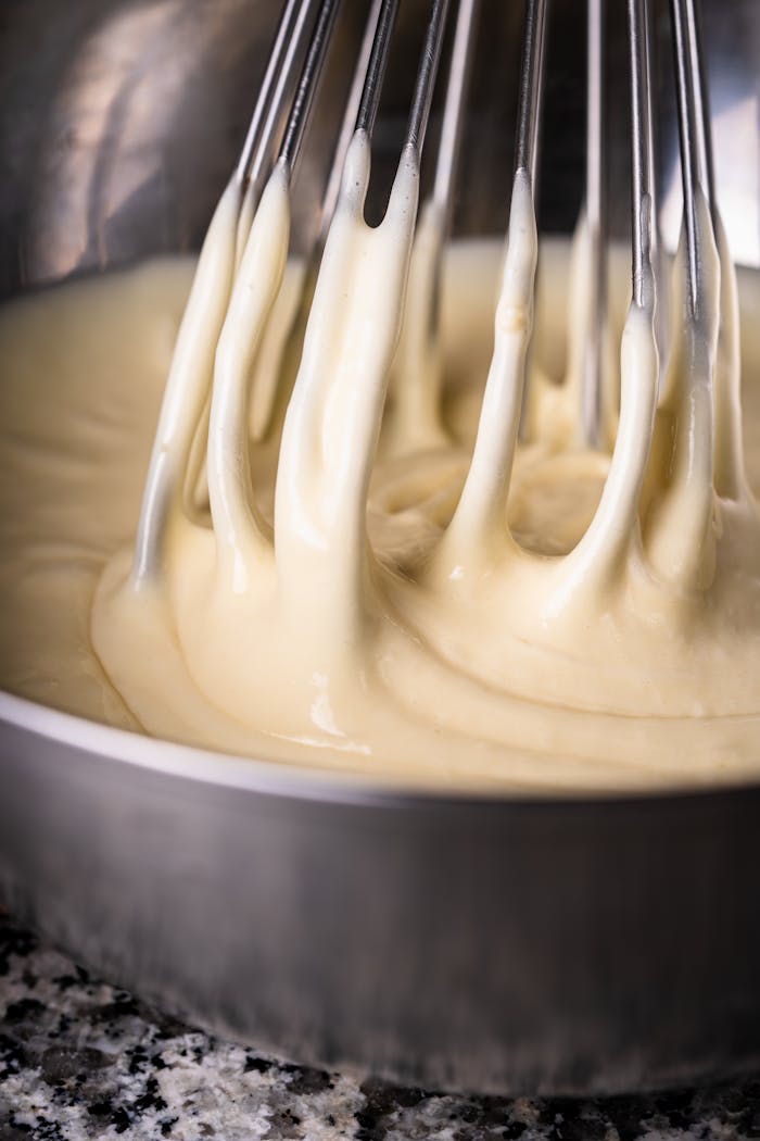 Smooth and creamy batter being whisked in a metal bowl, perfect for baking projects.