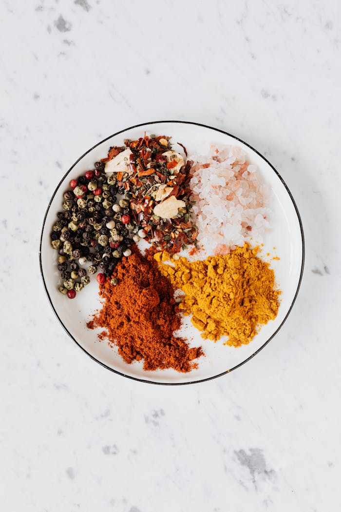 why-choose-us From above of bowl filled with piled of turmeric and paprika powder near mix of pepper flakes and seeds with sea salt on table