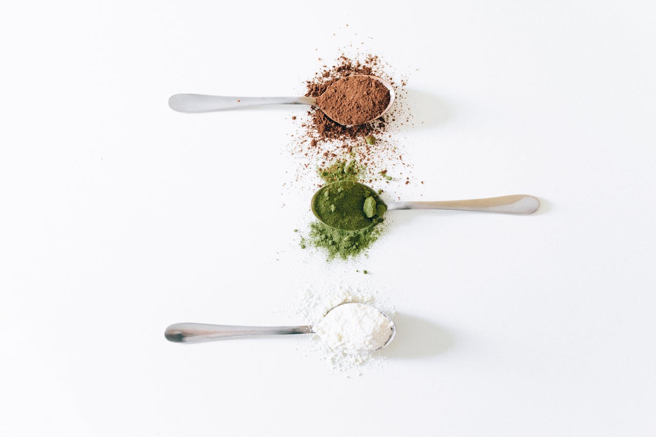 who-we-are Top view of colorful assorted powders on spoons against white background.